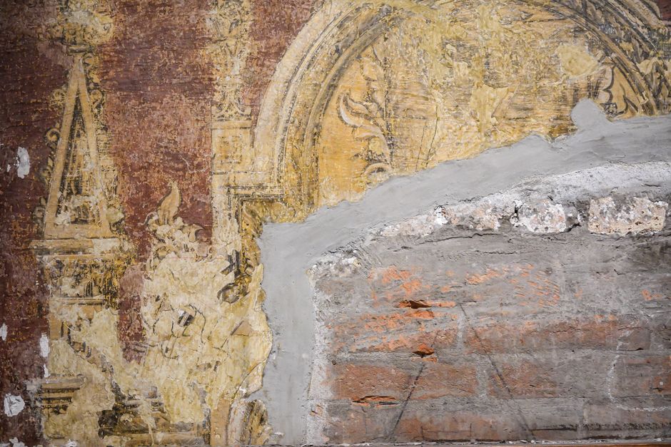 A partially restored ancient fresco depicting intricate designs on a palace wall.